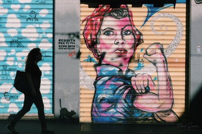 Una donna cammina davanti a un murale femminista