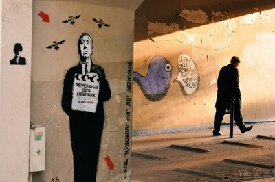 Un uomo cammina per le strade del 5° arrondissement a Parigi, circondato da graffiti di artisti di strada