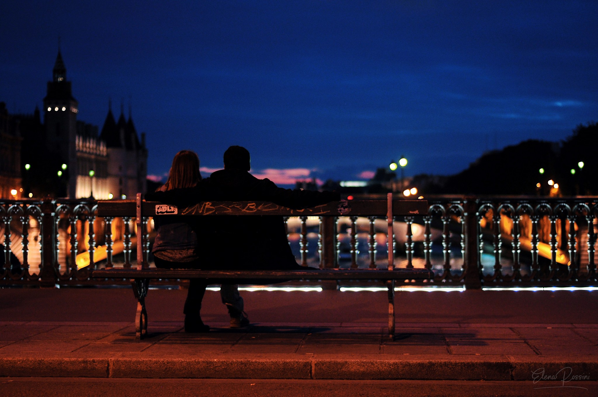 Una coppia seduta su una panchina osserva le barche che passano sulla Senna al crepuscolo - Pont Au Change, Parigi