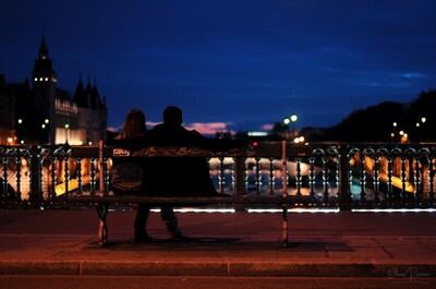 Una coppia seduta su una panchina osserva le barche che passano sulla Senna al crepuscolo - Pont Au Change, Parigi